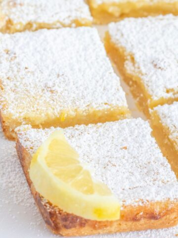 Lemon bars on the counter top with lemon slices on top.