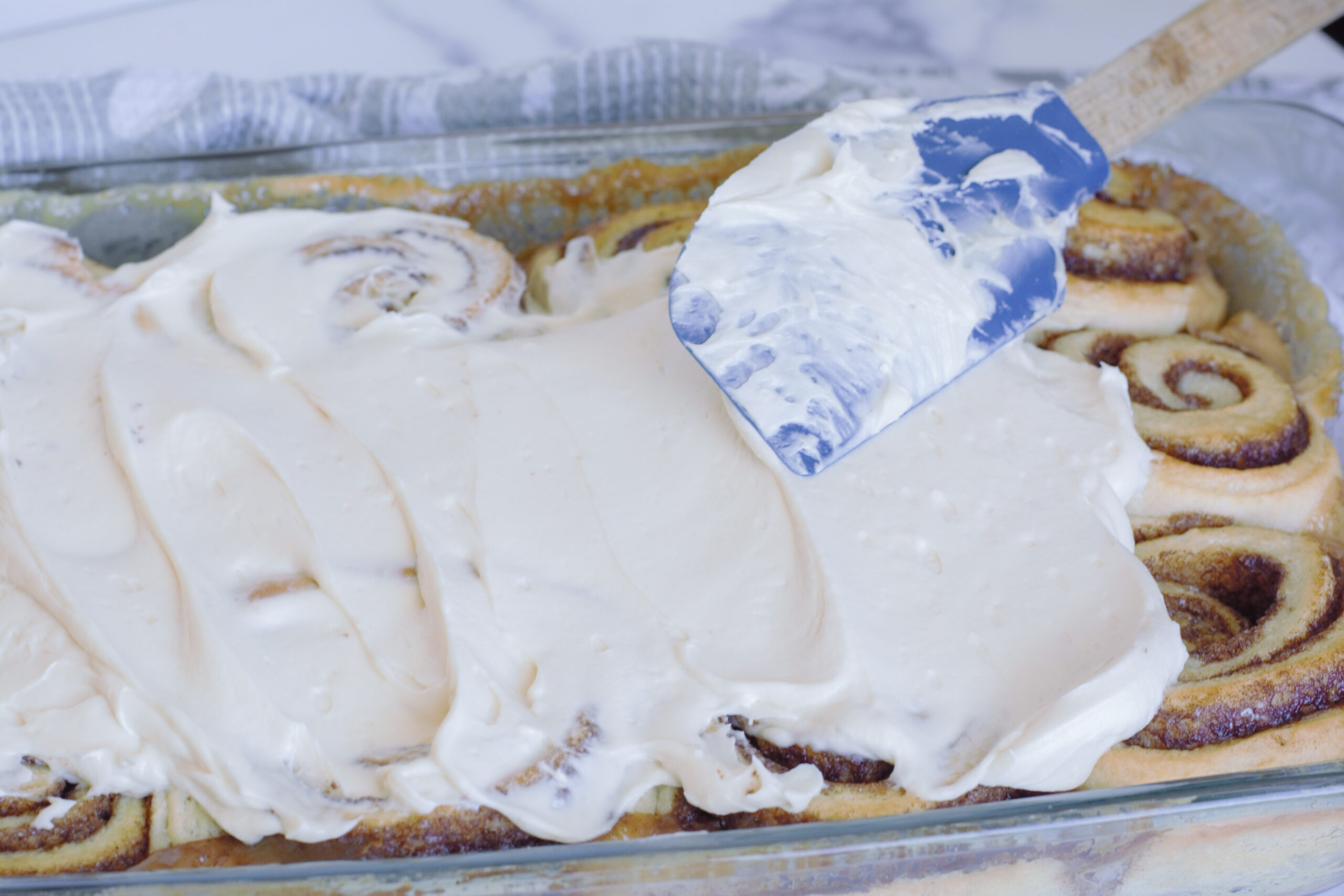 Frosting the rolls with a spatula.