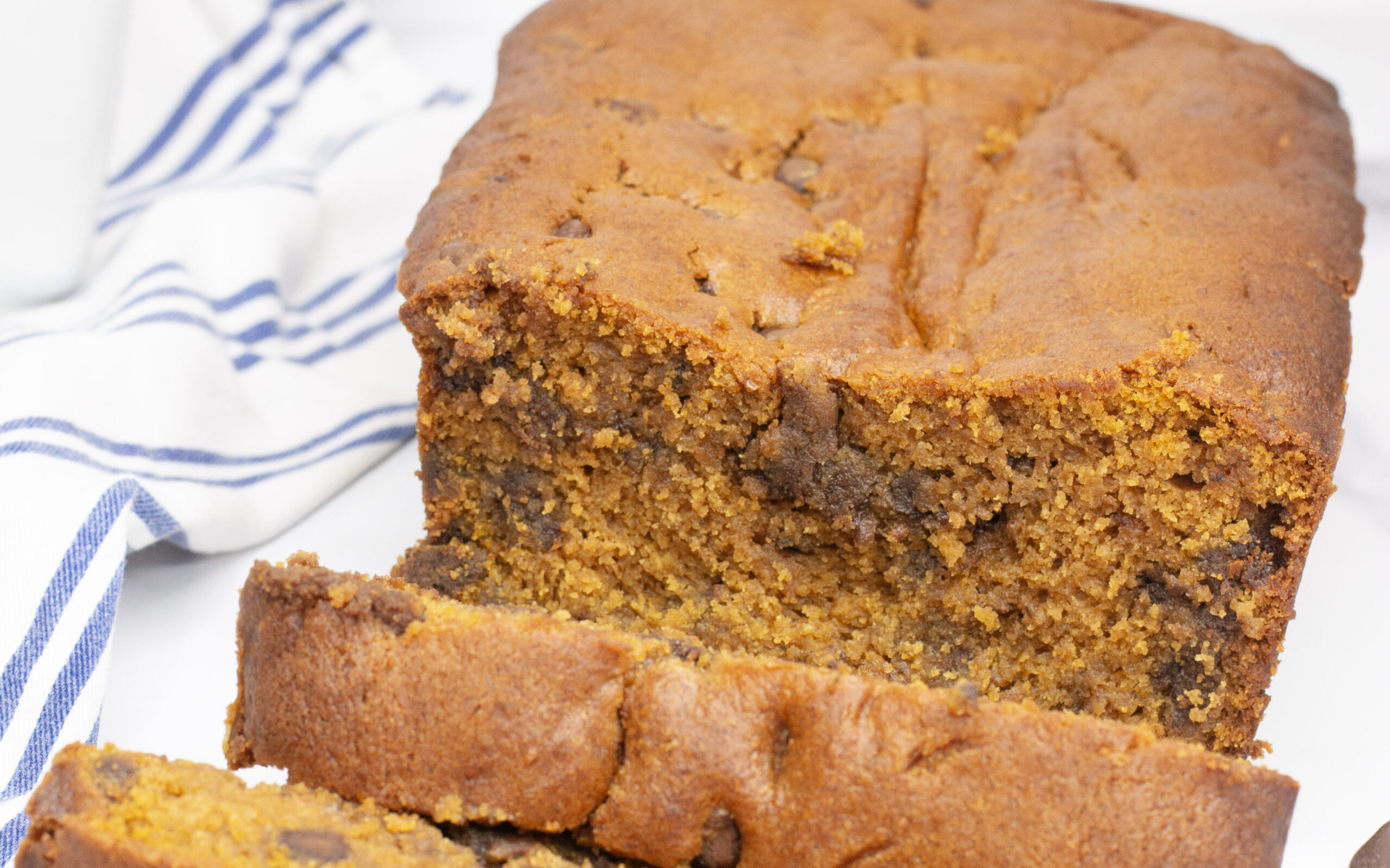 Cooked pumpkin bread on a cutting board cut into slices.