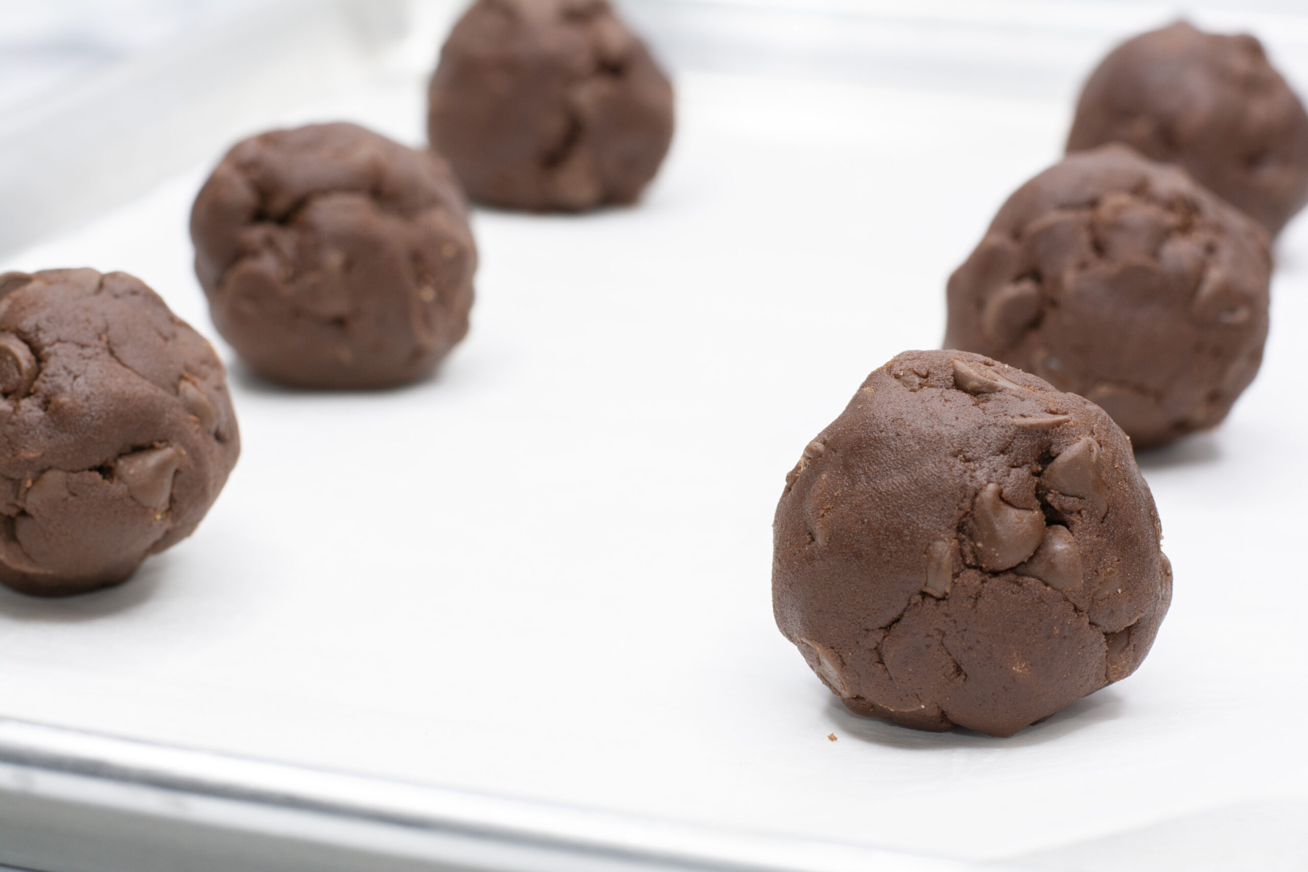 Cookie dough rolled into balls and placed on a pan.