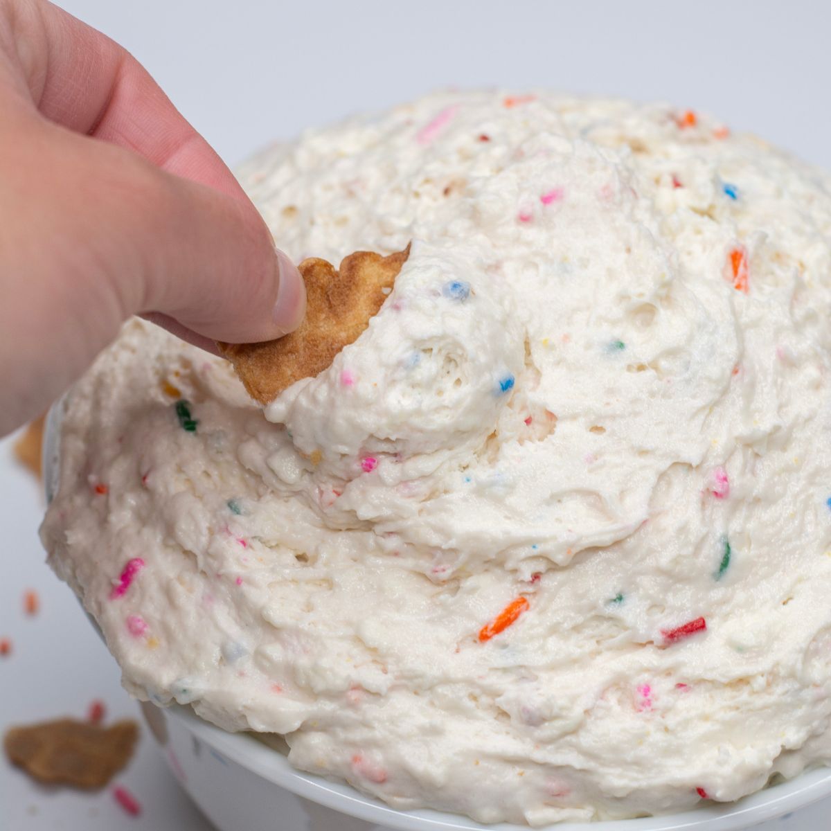 Waffle cone dipping in the funfetti cake batter dip