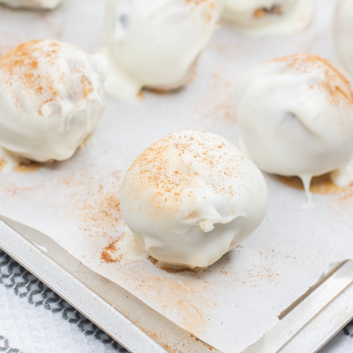 Pumpkin cookie dough truffles coated in white chocolate and sprinkled with cinnamon.