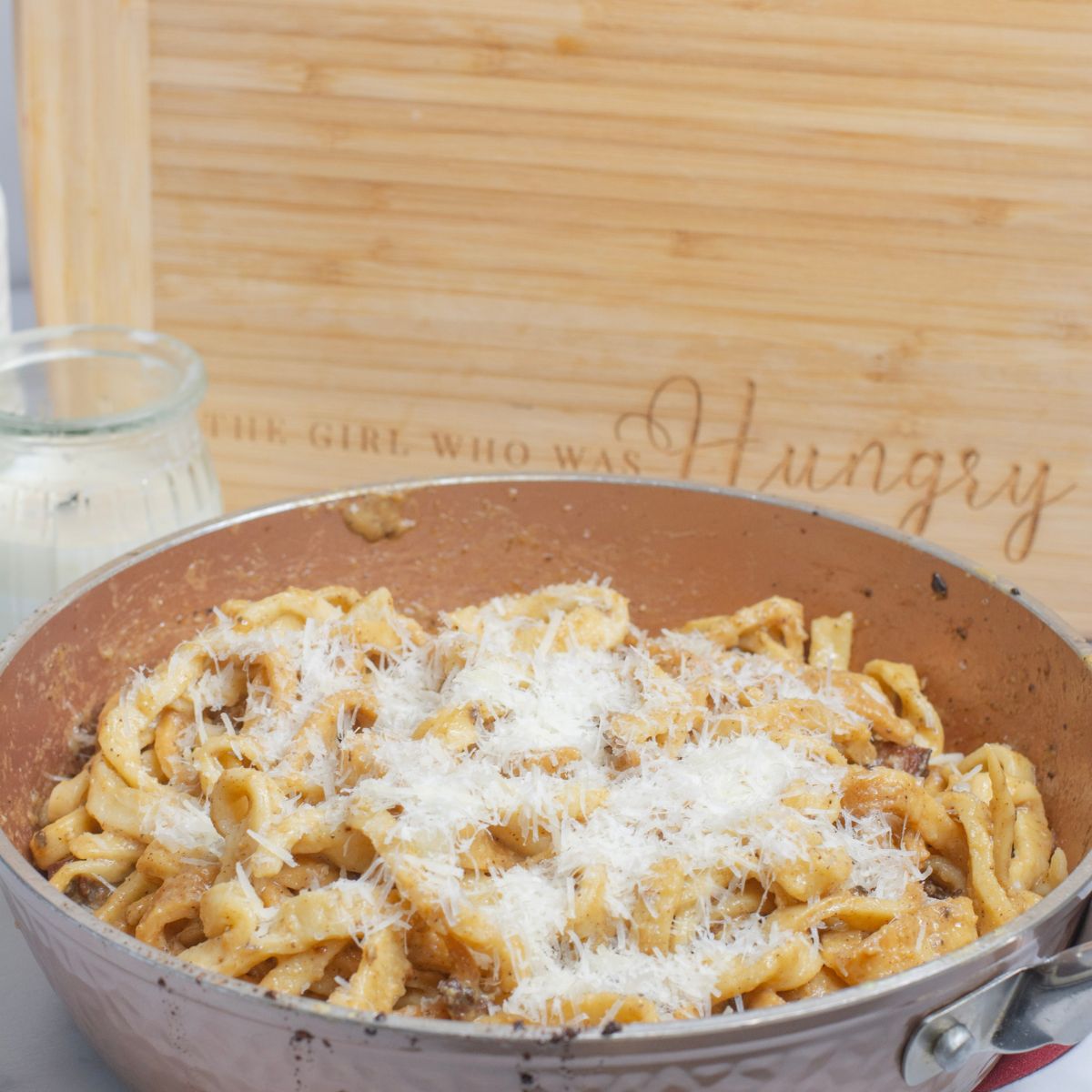 Carbonara traditional recipe with eggs in a pan with grated cheese on top.