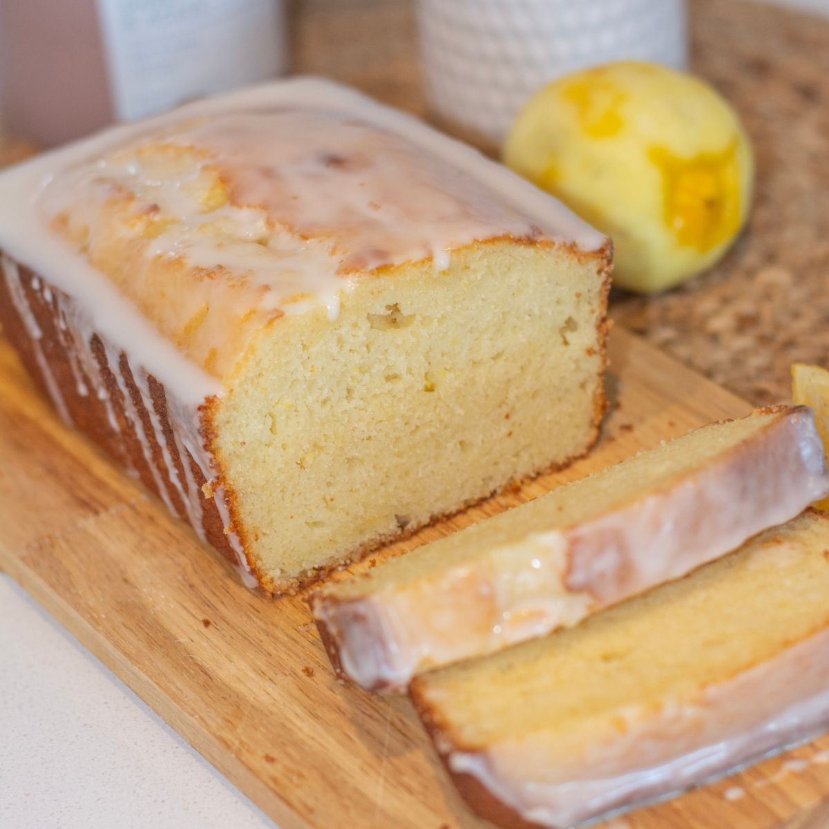 Starbucks copycat lemon loaf on a cutting board with real lemons 