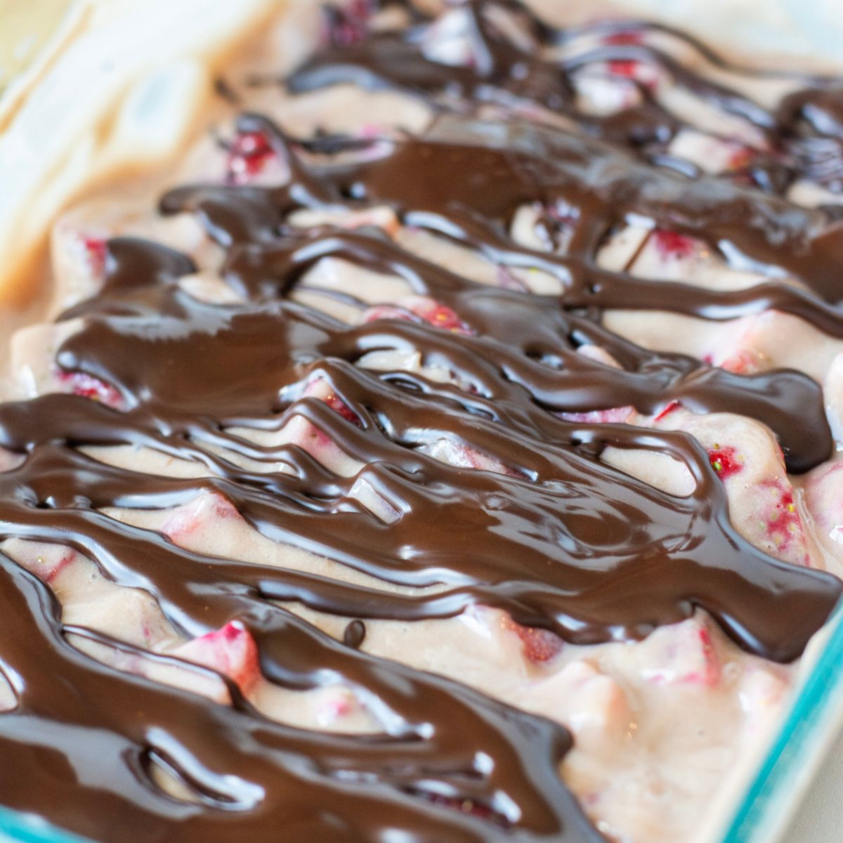 dark chocolate drizzled over the top of a mixture of strawberries, yogurt and protein powder