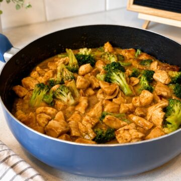 Peanut butter chicken in a frying pan with broccoli