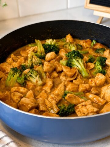 Peanut butter chicken in a frying pan with broccoli