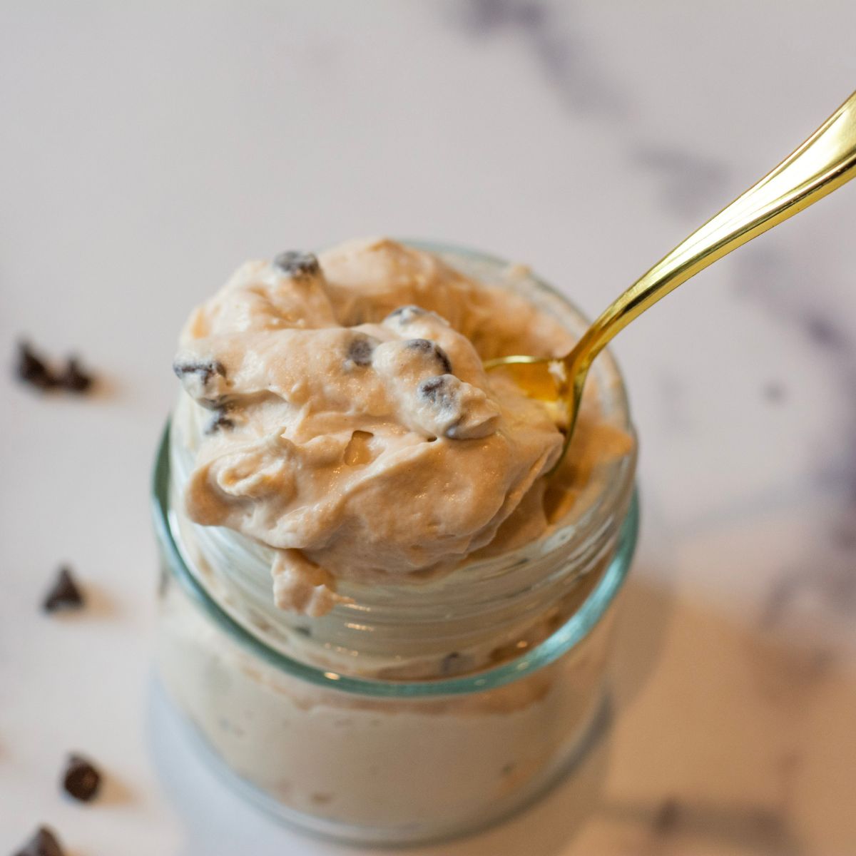 creamy chocolate protein cheesecake yogurt fluff getting spooned out of a container.