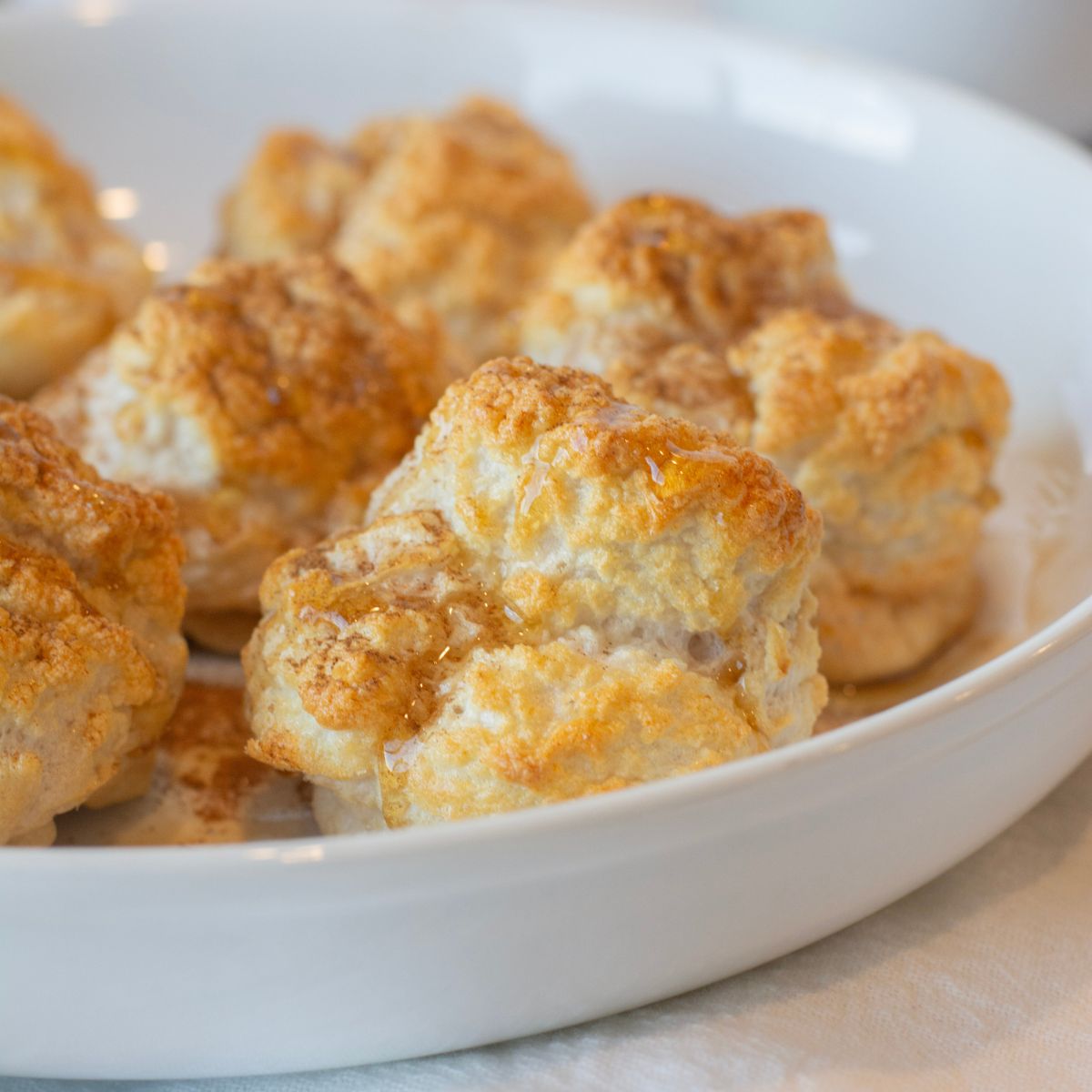 High-protein fluffy cinnamon bites on a plate with a drizzle of maple syrup on top.