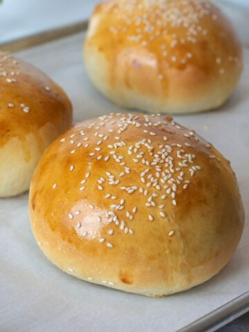 Homemade hamburger buns placed on a baking sheet and cooked until golden.