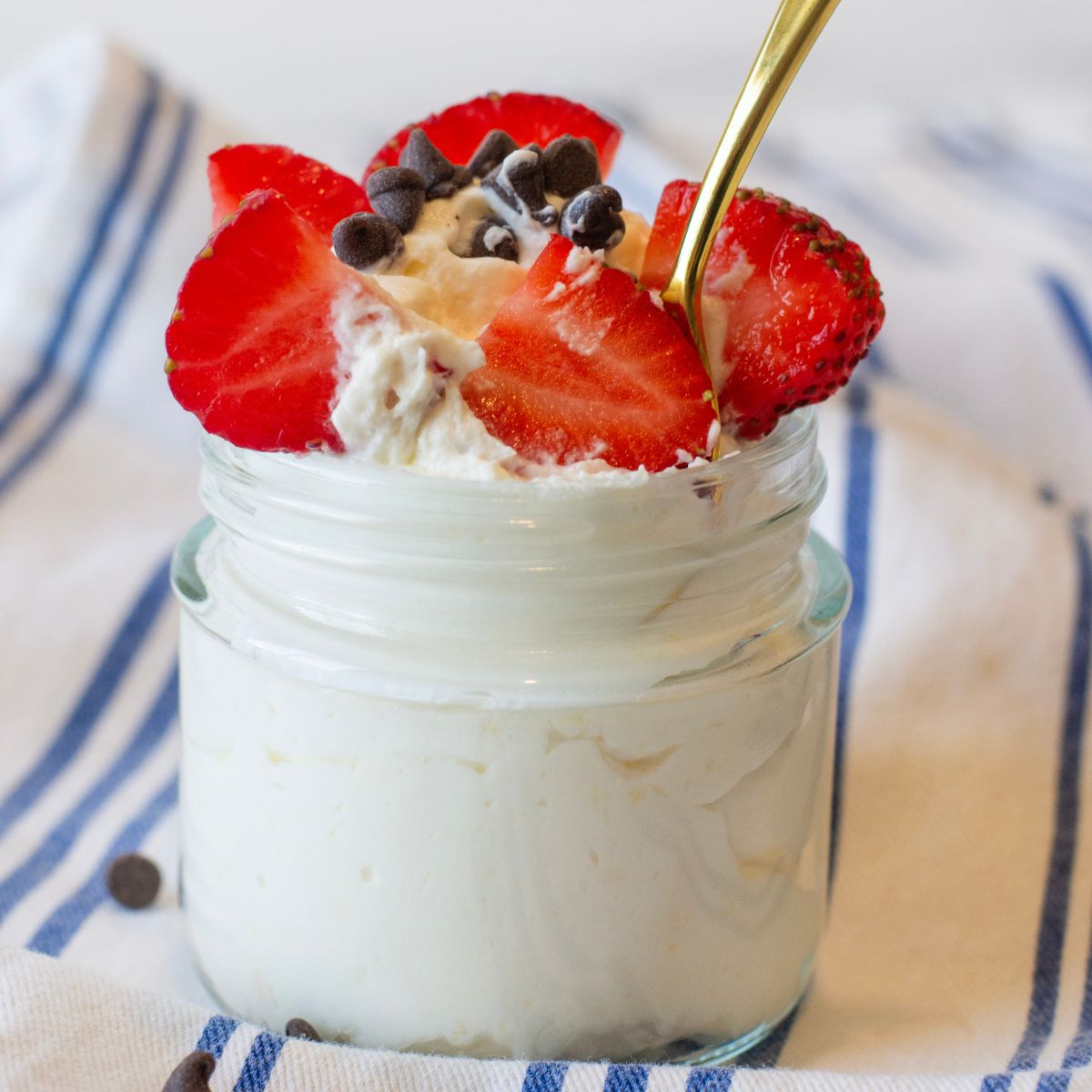 Protein Cheesecake Yogurt Fluff in a glass container with a gold spin sticking in it.