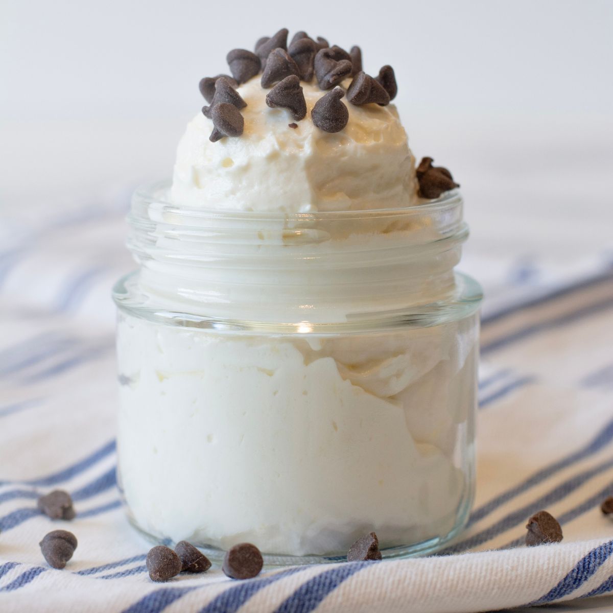 Protein Cheesecake Yogurt Fluff topped with mini chocolate chips and super fluffy and creamy yogurt scooped into a glass cup.