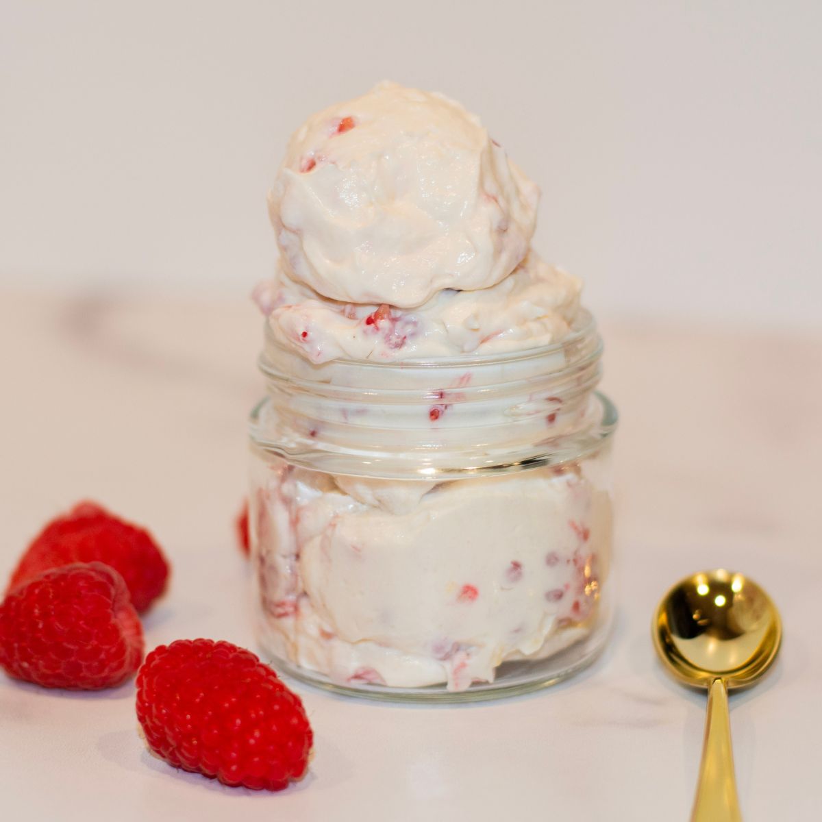 Protein yogurt and cheesecake fluff in a bowl with a golden spoon next to it.