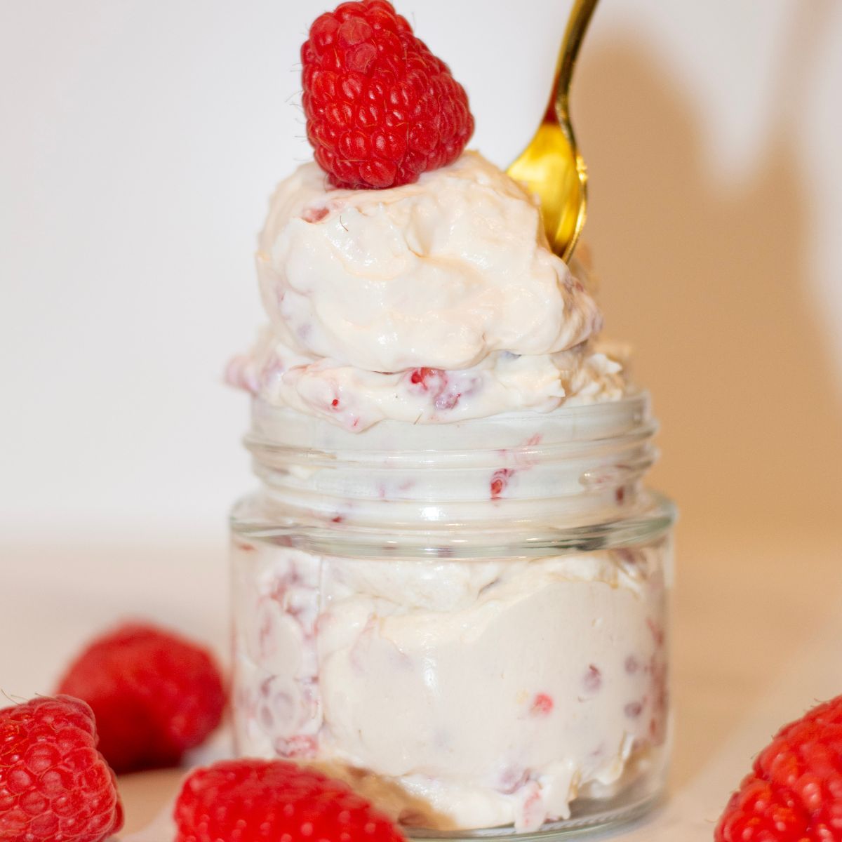 Raspberry Cheesecake Protein Jello in a bowl with raspberries on top.